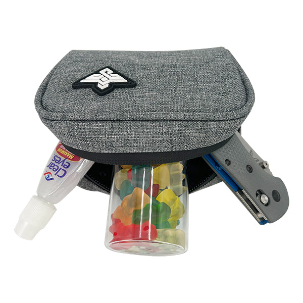 A partially unzipped Erozul Nano Small Smell Proof Slim Pack Pouch V2.0 with 5-layer technology holds a tube of eyedrops, a clear gummy bear container, and a gray utility knife.