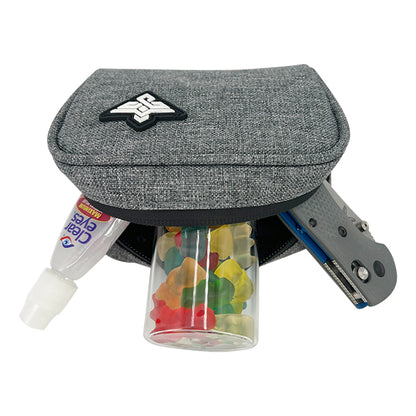 A partially unzipped Erozul Nano Small Smell Proof Slim Pack Pouch V2.0 with 5-layer technology holds a tube of eyedrops, a clear gummy bear container, and a gray utility knife.