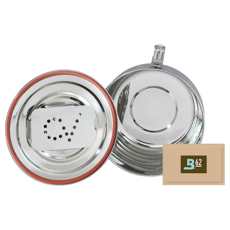 Two stainless steel round containers, one with a vented insert and a red seal, and a small rectangular brown packet labeled B62 next to them.